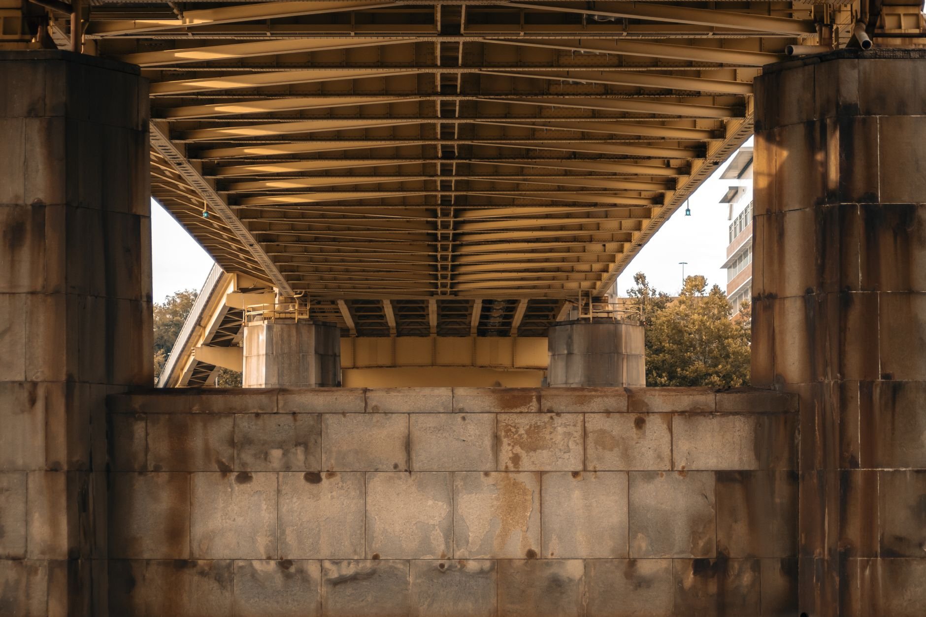 A detailed view of a yellow steel bridge underpass in Pittsburgh showcasing industrial architecture.
